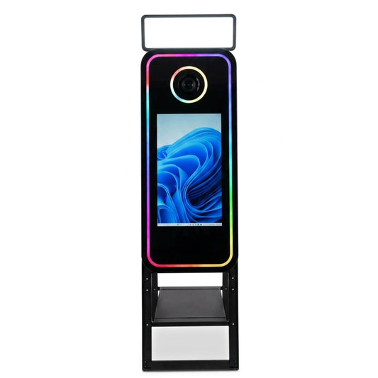 Una imagen de producto de alta calidad de un fotomatón espejo mágico con una pantalla táctil de 45 pulgadas, que muestra su marco de luces LED RGB de colores vibrantes, un anillo de luz circular DSLR y un estante de múltiples niveles, todo sobre un fondo blanco